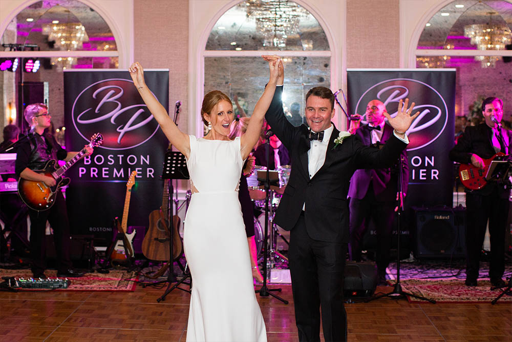 A happy bride and groom raise their arms after performing their first dance performed by Boston Premier, a Boston wedding band from Massachusetts.