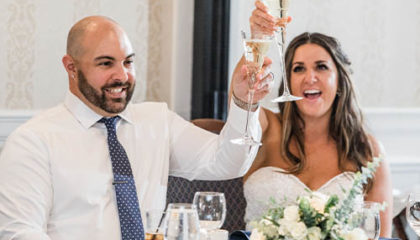 The Bride and Groom Raising their toast glasses at their head table.