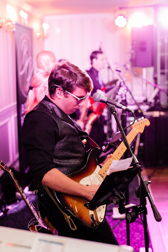 The guitarist of the Boston wedding band plays a solo while wedding guests dance.