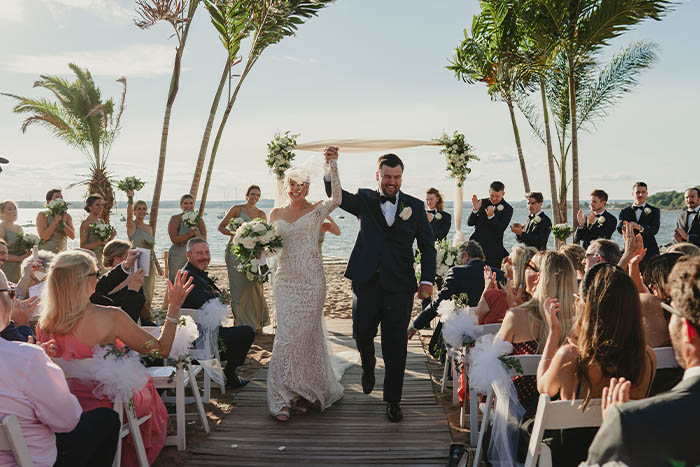 The Bride and Groom raise their arms in joy as they leave the ceremony