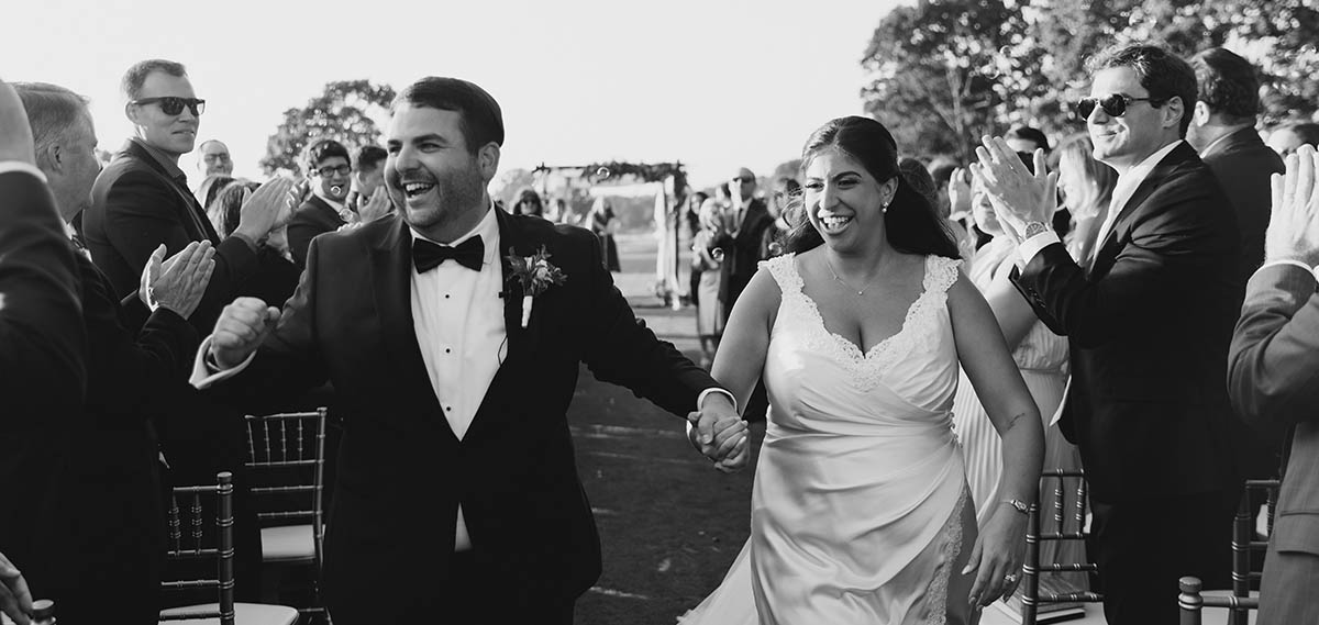 The bride and groom leaving their ceremony smiling at their guests.