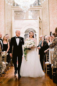 A photo of the bride being escorted down the aisle by her father in the Salon Room.